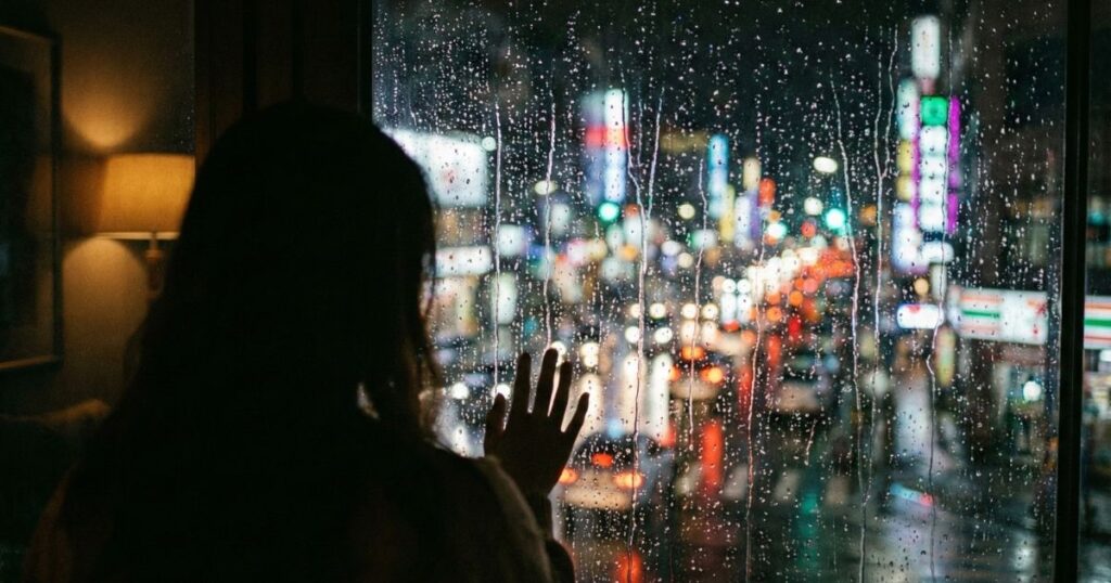 Persona sintiéndose separada del mundo exterior por un cristal, representando ansiedad social y agorafobia.